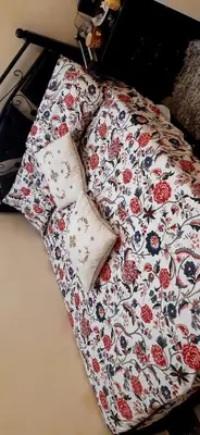 a bed with a flowered blanket and two pillows on it at Zitouna Rooms in Casablanca