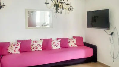 a pink couch in a living room with a tv at Comfortable Apartment with Pool in Tamaris - 75 m² - Sea View in Dar Bouazza