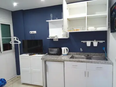 a kitchen with white cabinets and a blue wall at Studios Taha in Rabat