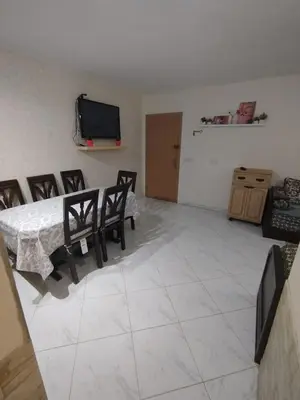 a living room with a table and chairs and a tv at appartement plage Bouznika in Bouznika