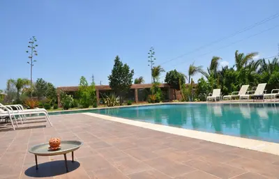 a swimming pool with chairs and a table next to it at Riad Hamdani in Casablanca