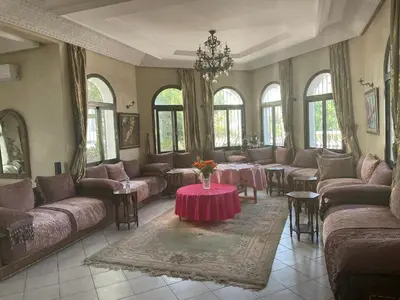 a living room with couches and tables and windows at Aux Moules de Harhoura Rabat in El Harhoura