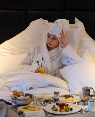 a woman laying in bed with a tray of food at Le Casablanca Hotel in Casablanca