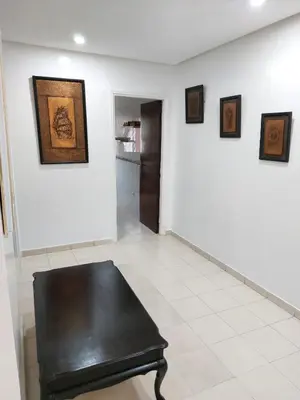 a black bench in a white room with pictures on the wall at Apartment in the city center, 2 minutes walk from the tram in Rabat