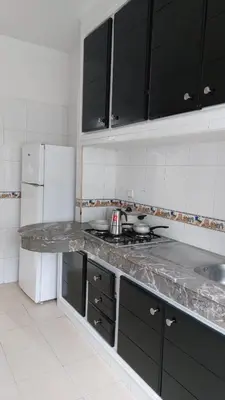 a kitchen with black cabinets and a white refrigerator at Apartment in the city center, 2 minutes walk from the tram in Rabat
