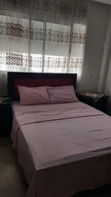a bedroom with a large bed with white sheets at Agdal Two-Bedroom Apartment 2 Minutes from Agdal Train Station in Rabat