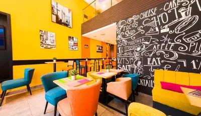 a restaurant with yellow walls and tables and chairs at RENT-INN Suites Hotel in Rabat