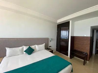a bedroom with a large bed with a green blanket at Hotel Azur in Casablanca