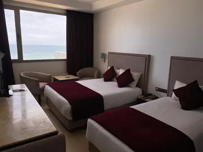 a hotel room with two beds and a window at Hotel Azur in Casablanca