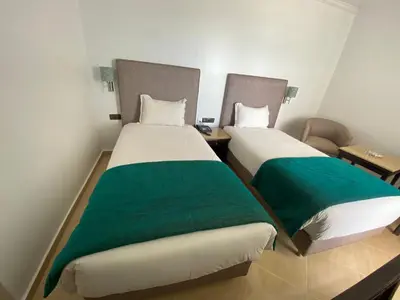 two beds in a room with green and white sheets at Hotel Azur in Casablanca