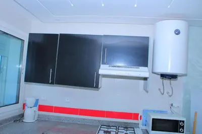 a kitchen with black and white cabinets and a microwave at Jnane Eddalya in Bouznika