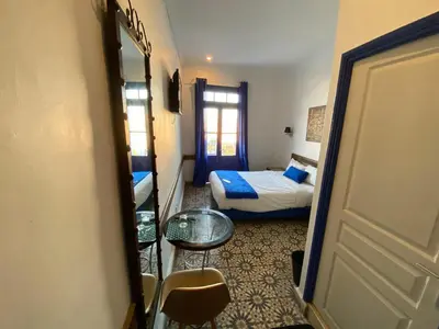 a room with a bed and a table and a door at Hôtel Central in Casablanca