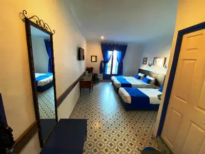 a hotel room with two beds and a mirror at Hôtel Central in Casablanca
