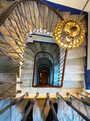 a group of people are reaching up for a spiral staircase at Hôtel Central in Casablanca