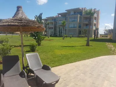 two chairs and an umbrella next to a building at Evasion Bouznika أمام شاطىء بوزنيقة in Bouznika