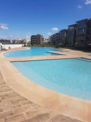 a large swimming pool with blue water and buildings at Evasion Bouznika أمام شاطىء بوزنيقة in Bouznika