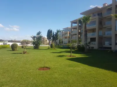 a large yard with palm trees and a building at Evasion Bouznika أمام شاطىء بوزنيقة in Bouznika
