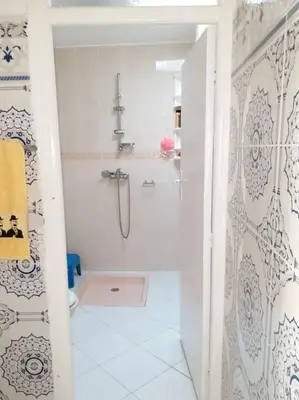a white bathroom with a shower and a toilet at Villa Close To The Beach in Temara