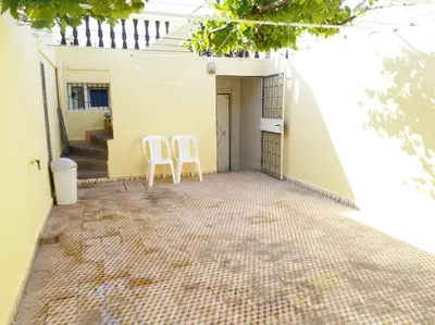 two white chairs sitting on the outside of a house at Villa Close To The Beach in Temara