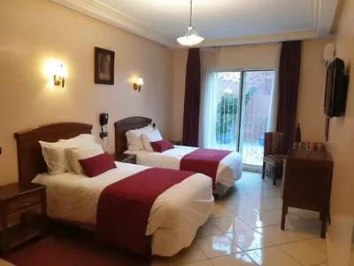 a hotel room with two beds and a television at Hôtel Amouday in Casablanca