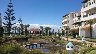 a resort with a pond and a bridge and buildings at Garden Beach Sidi Rahal in Sidi Rahal
