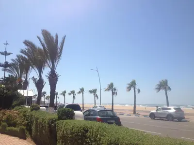 a group of cars parked on a road next to the beach at Garden Beach Sidi Rahal in Sidi Rahal