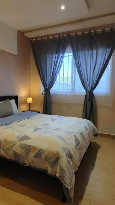 a bedroom with a large bed with blue curtains at Herb studio in Casablanca (800 m from Casavoyageurs station) in Casablanca