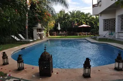 a swimming pool with a fountain in front of a house at Riad Alhambra in El Harhoura
