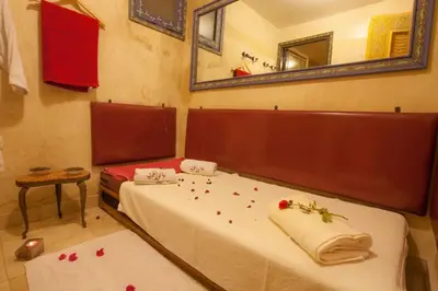 two beds in a room with red rose petals on them at Riad Alhambra in El Harhoura