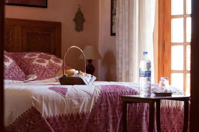 a bed with a basket and a bottle of water on a table at Riad Alhambra in El Harhoura