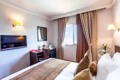 a hotel room with a bed and a television at Relax Hotel Airport Nouasseur in Nouaseur