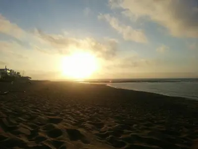 a sunset on a beach with the sun in the sky at Les perles de tamaris dar bouazza in Dar Mohammed Ould Haj Jilali