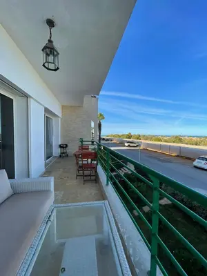 a balcony with a couch and a view of the ocean at Les perles de tamaris dar bouazza in Dar Mohammed Ould Haj Jilali