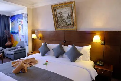 a bedroom with a large white bed with a wooden headboard at Washington Hotel in Casablanca