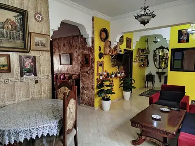 a living room with a bed and a table and yellow walls at Marguerite Apartemnt dans une résidence familiale in Casablanca