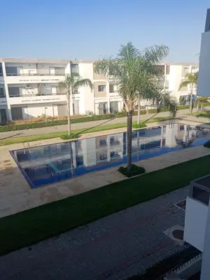 a swimming pool with palm trees in front of a building at Marbella Beach Residency in Mansouria