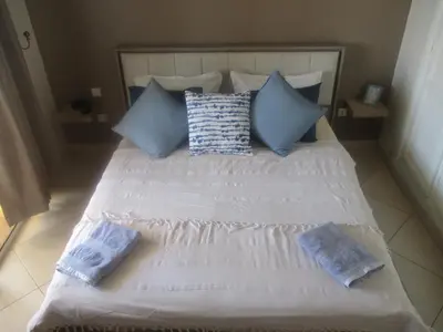 a large white bed with blue pillows on it at Appartement Casablanca Garden Beach in Casablanca