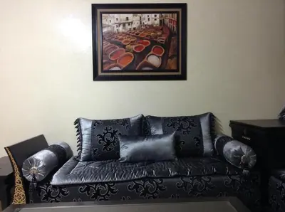 a black leather couch in a living room with a painting at Cosy Appartement Rabat Haut Agdal in Rabat