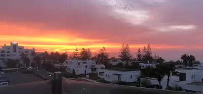 a sunset over a city with white buildings and trees at Villa meublée face à la mer, Golf et Verdure in El Jadida