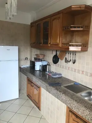 a kitchen with wooden cabinets and a white refrigerator at Résidence les Ambassadeurs in Rabat