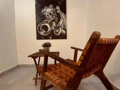 a wooden chair sitting in a room with a painting at Calm&cosy appart very well located in Casablanca