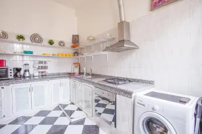 a white kitchen with a washer and a checkered floor at appartement haussmannien centre ville Casablanca in Casablanca