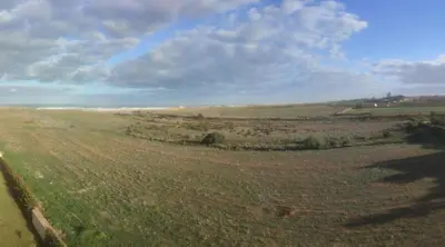 an open field with grass and a cloudy sky at appartments front mer in Bouznika