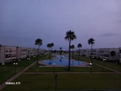 a pool in a park with palm trees and buildings at Ola Blanca 1 in Dar Hamida