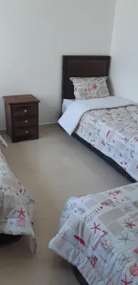 a bedroom with two beds and a night stand at Ola Blanca 1 in Dar Hamida