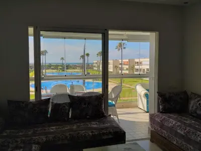 a living room with a couch and a view of a pool at Ola Blanca 1 in Dar Hamida