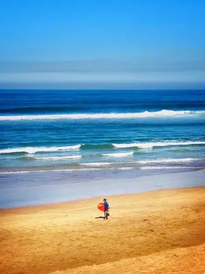 a person walking on the beach with a surfboard at Marbella Beach location pour famille 2 chambres in Mansouria