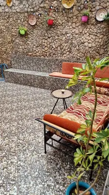 a bench and a table in front of a stone wall at Location Vacances Casablanca Tamaris in Casablanca