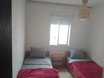 two beds sitting in a room with a window at Appartement in Casablanca close to the beach in Casablanca