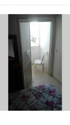 a bedroom with a bed and a glass door with a chair at Appartement in Casablanca close to the beach in Casablanca
